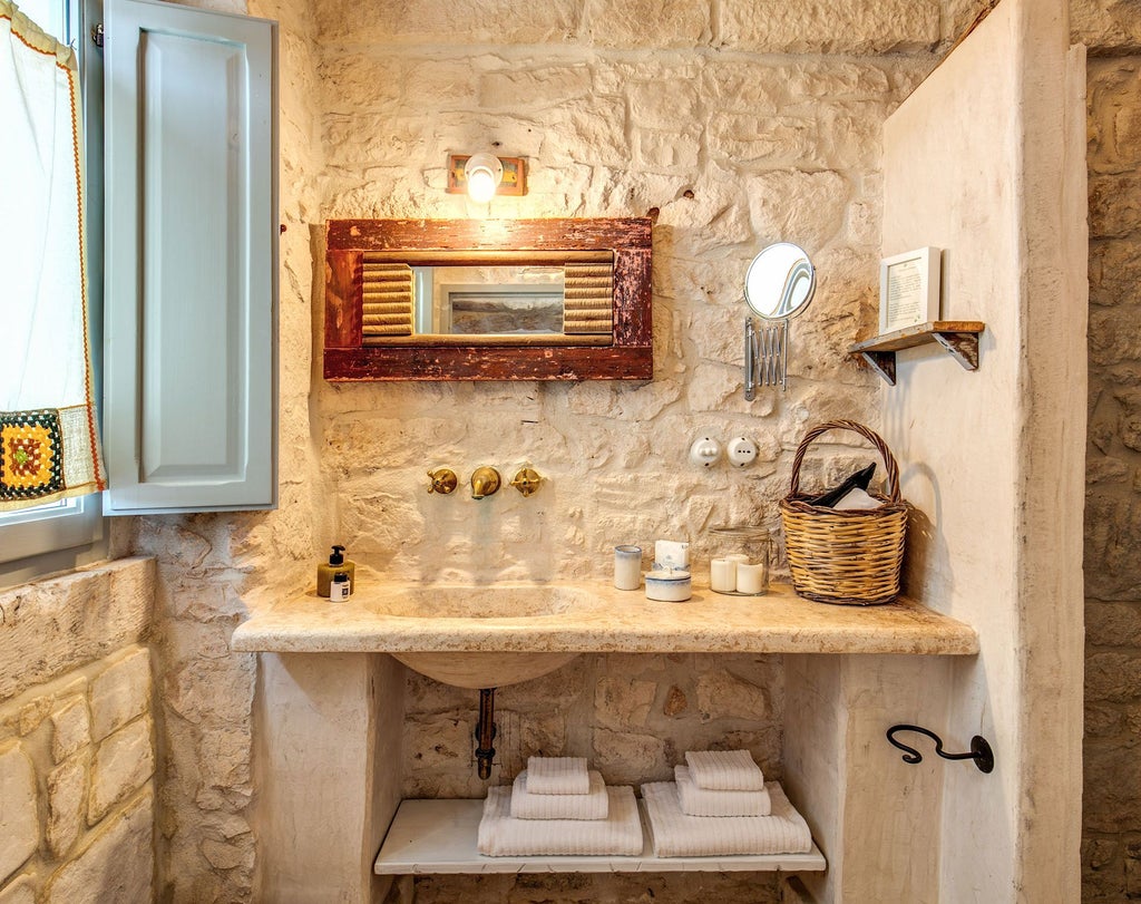 Rustic-chic junior suite at Masseria Cervarolo with soft white linens, stone walls, and elegant wooden furnishings in a traditional Apulian farmhouse setting