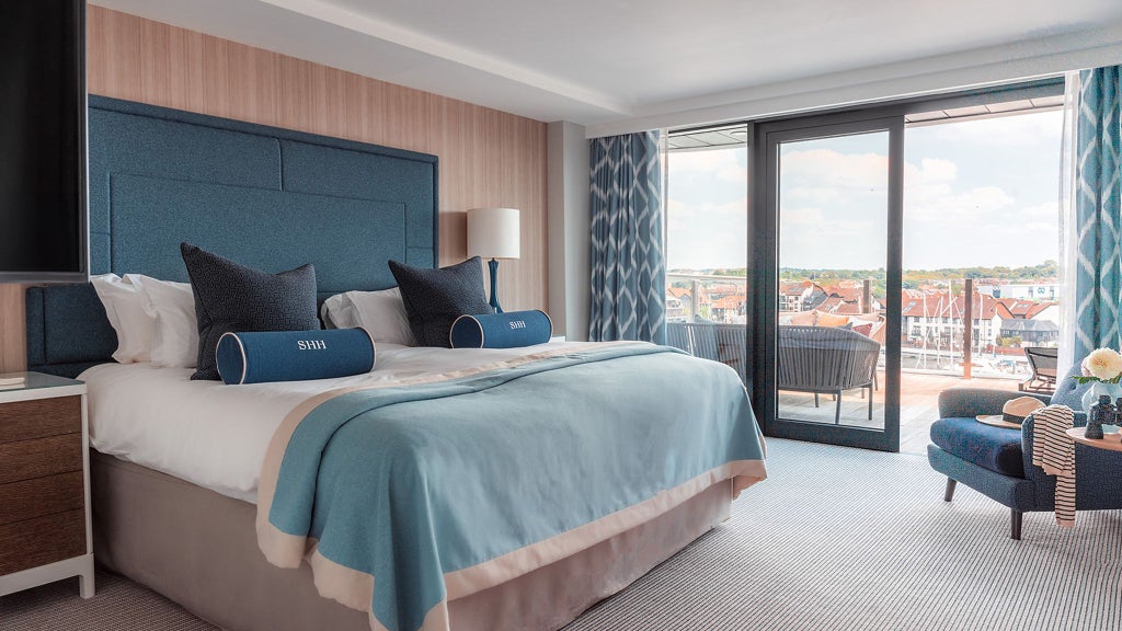 Spacious deluxe marina view suite with private balcony, modern furnishings, and panoramic water views at Harbour Hotel Southampton, United Kingdom.