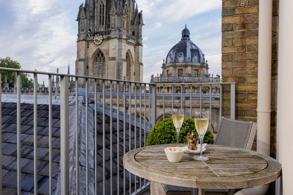 Elegant Victorian-era hotel room with polished wooden furnishings, plush white bedding, and tall windows overlooking historic urban scenery in a classic United Kingdom setting