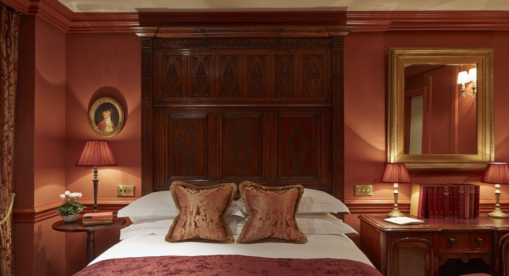 Elegant boutique hotel room with plush blue velvet headboard, vintage-inspired furnishings, and soft ambient lighting in a luxurious London accommodation.