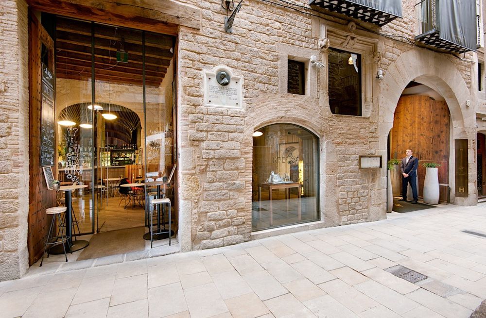 Elegant Hotel Mercer facade showcases Spanish colonial architecture with grand stone archways and ornate wrought-iron balconies at dusk