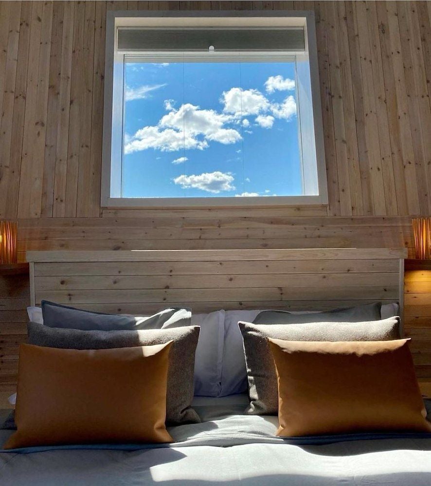 Minimalist wooden cabin interior with floor-to-ceiling windows, overlooking frozen river, scandinavian design featuring clean lines and natural materials at Arctic Bath hotel