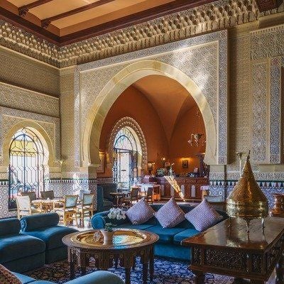 Historic luxury palace-hotel with ornate Moorish architecture, stone archways and lush garden courtyard set against Granada mountains