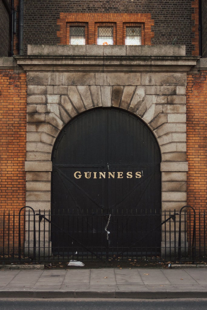 Dark wooden barrel displays and gleaming copper brewing equipment at Guinness Storehouse, showcasing traditional Irish brewing craftsmanship with soft atmospheric lighting