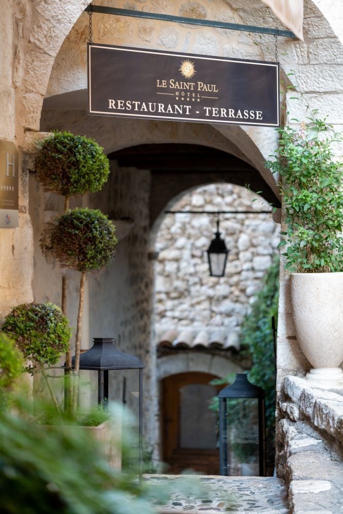 Elegant stone facade of boutique hotel in Saint-Paul-de-Vence, nestled in charming French village with warm terracotta roofs and medieval architecture