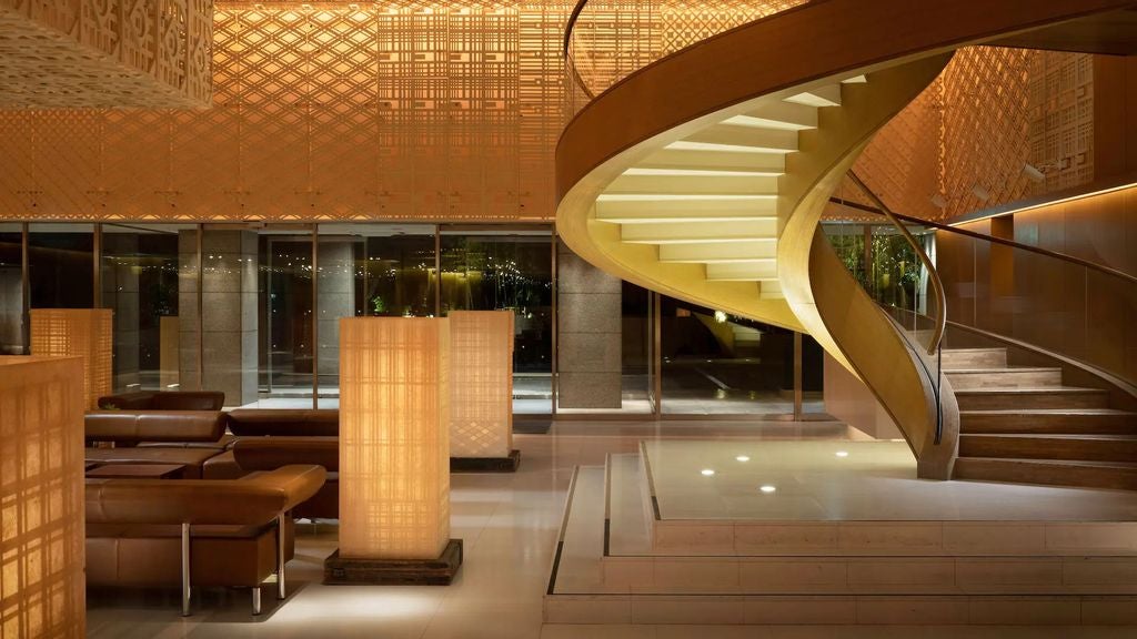 Grand Hyatt Regency hotel in Tokyo featuring modern glass facade, illuminated entrance with marble pillars and sleek water feature at dusk