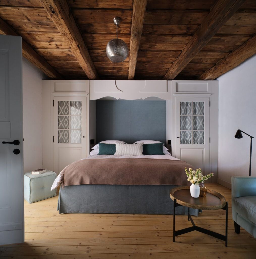 Elegant rustic bedroom in Transylvanian countryside, featuring warm wooden floors, traditional textiles, and antique furnishings with soft natural lighting