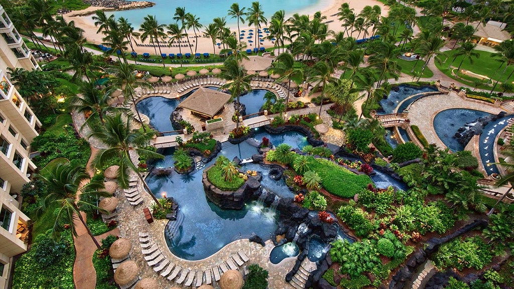 Luxurious beachfront resort with palm trees, azure waters, and modern Hawaiian-style architecture at Scenset's Ko Olina Beach Club in Hawaii.