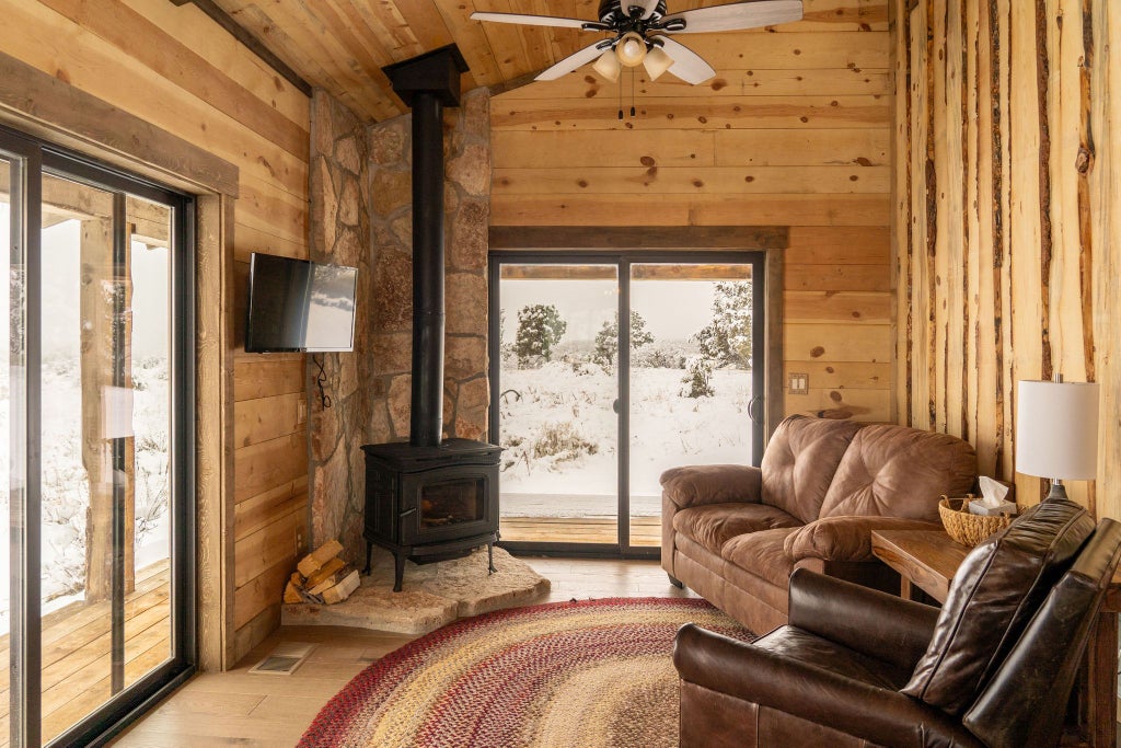 Rustic lodge room with wooden furnishings, plush bedding, and panoramic mountain views at a scenic ranch retreat near Zion National Park.