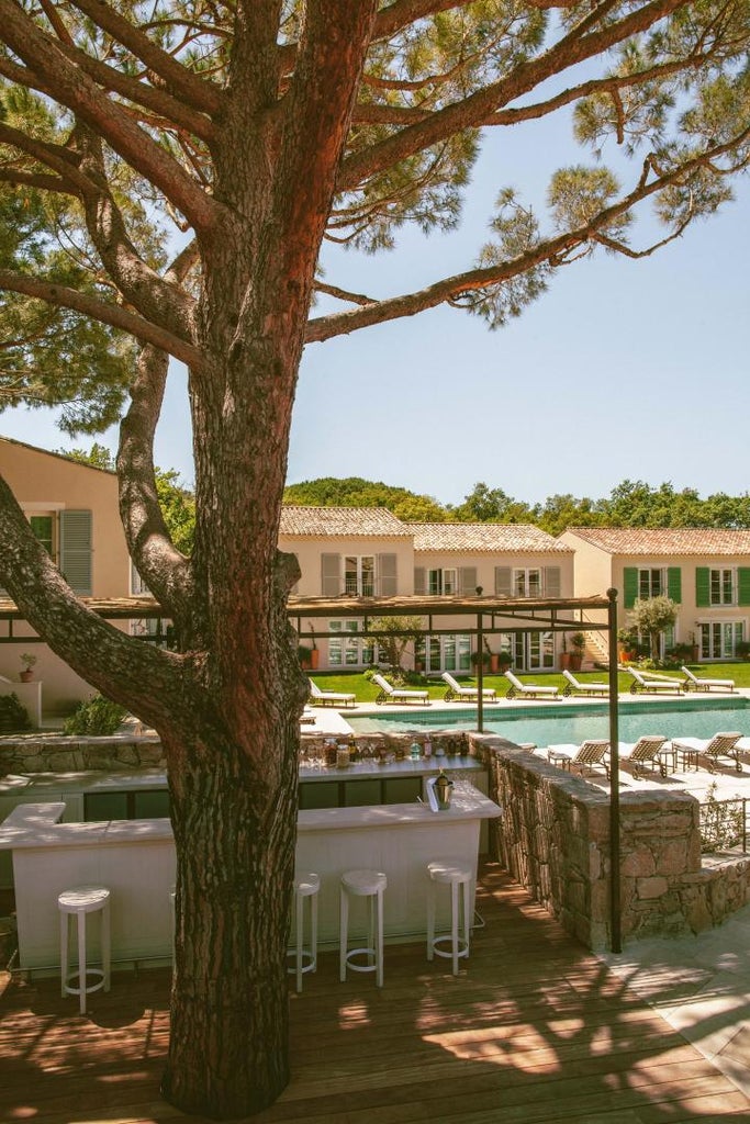 Luxurious stone-walled boutique hotel in Saint-Tropez surrounded by lush Mediterranean gardens, pine trees and terracotta accents