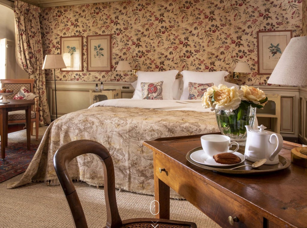 Elegant French hotel room with period furniture, ornate floral wallpaper, crystal chandelier and large windows with silk drapes