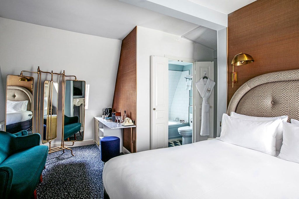 Elegant Parisian hotel room with plush burgundy headboard, vintage-inspired furnishings, and soft ambient lighting in boutique Grand Pigalle Hotel, France