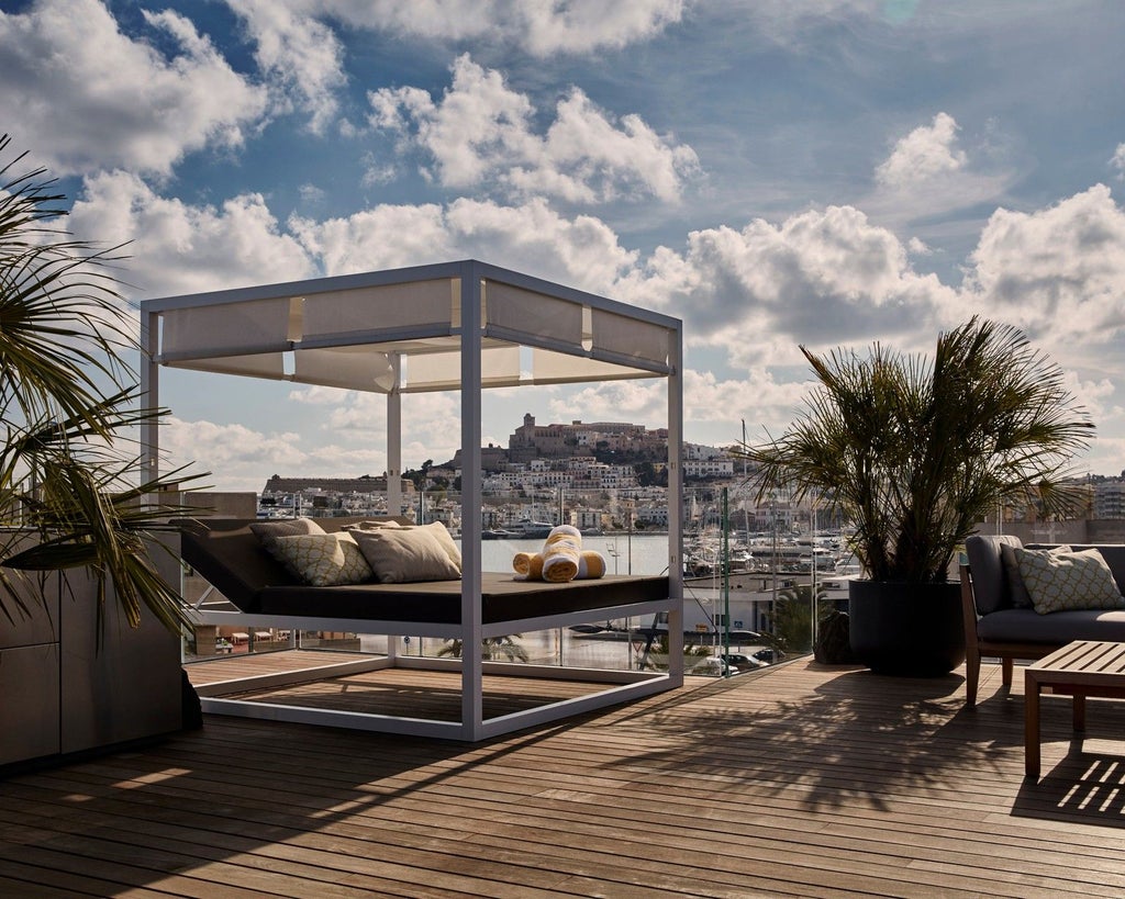 Luxurious white-themed penthouse suite with panoramic windows, modern minimalist design, and sweeping views of coastal scenery in Spain