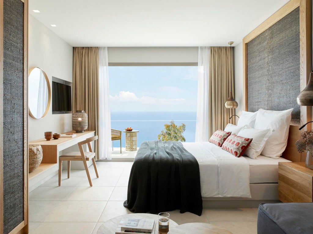 Elegant modern hotel room with panoramic azure Aegean Sea view, crisp white linens, minimalist design, and private balcony overlooking scenic Greek coastline