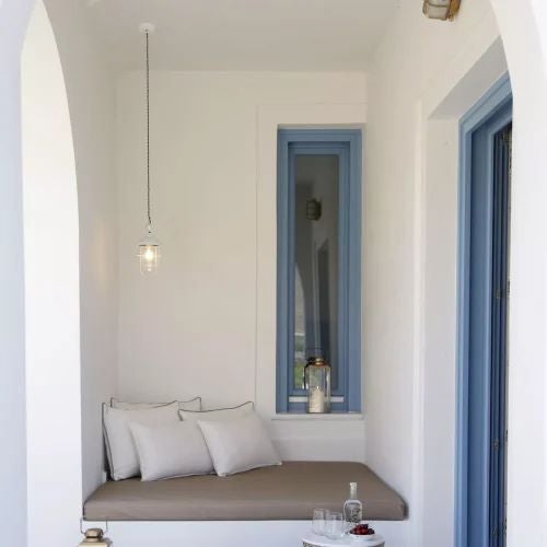 Luxurious Greek villa bedroom with stone walls, elegant wooden furnishings, crisp white linens, and panoramic view of scenic Mediterranean landscape