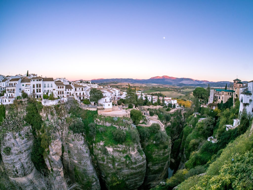 Whitewashed hillside village in Andalucia, Spain with traditional architecture, terracotta roofs, and panoramic mountain views at sunset