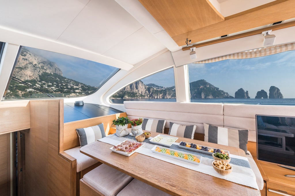 Elegant Italian yacht-hotel anchored in crystal-clear Mediterranean waters, featuring white exterior and expansive teak deck with loungers