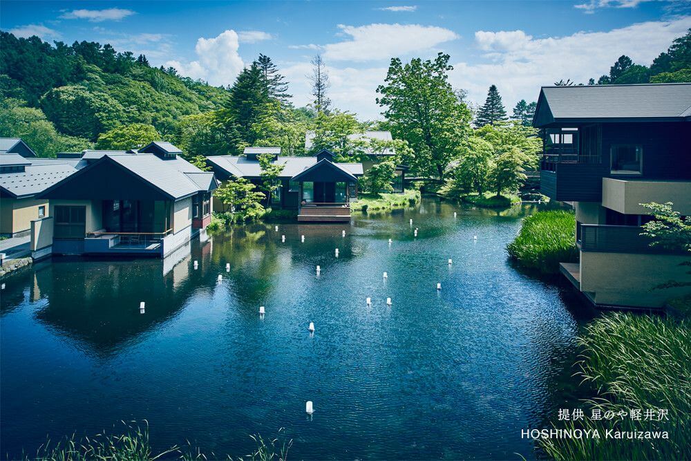 Luxurious Japanese ryokan with wooden terraces overlooking misty mountains, featuring traditional architecture and serene water features