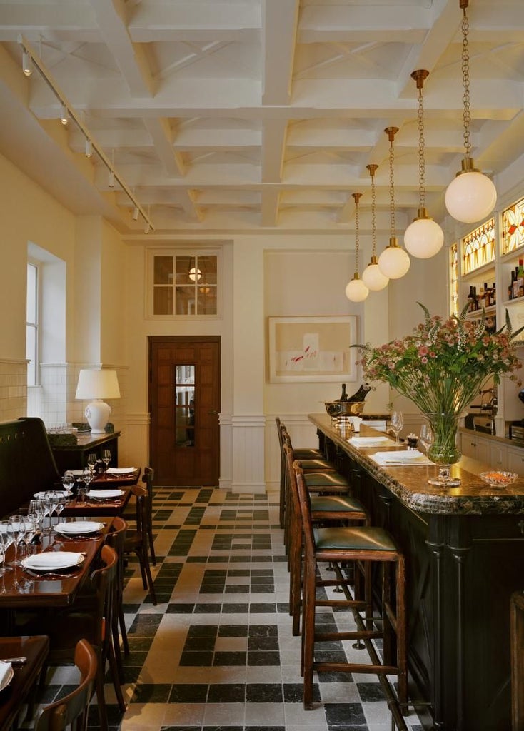 Elegant Parisian hotel exterior with neoclassical façade, soft cream-colored stone, ornate windows, and classic French architectural details at twilight