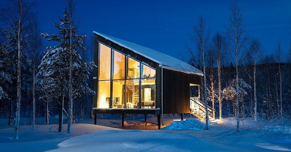 Spacious wooden land cabin family room at Arctic Bath, featuring minimalist Scandinavian design with warm timber textures and panoramic wilderness views in Sweden