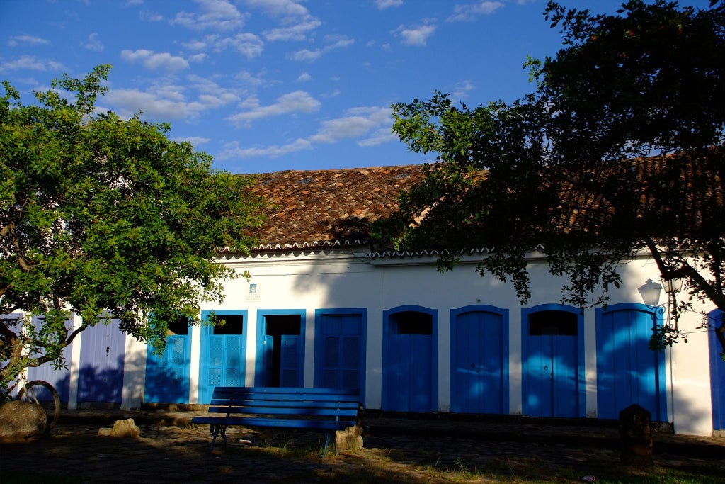 Elegant turquoise-hued boutique hotel with colonial architecture, lush tropical gardens, and luxurious pool nestled in scenic Brazilian landscape