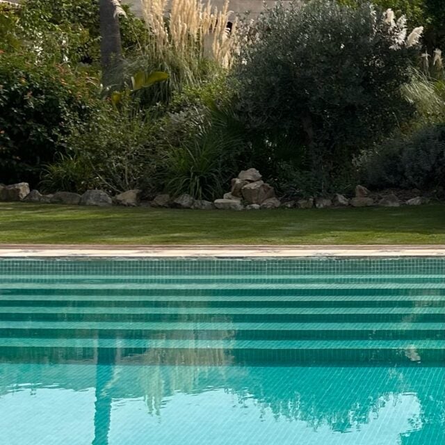 Elegant Spanish boutique hotel with whitewashed walls, terracotta roof tiles, and lush garden featuring a serene infinity pool