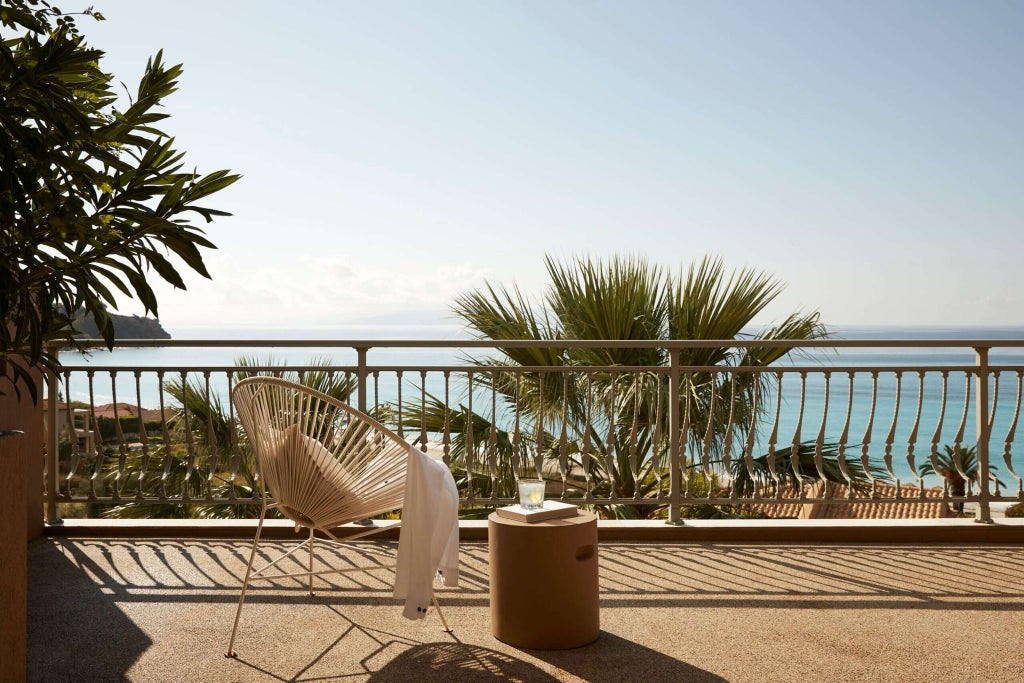 Luxurious infinity pool overlooking azure Ionian Sea, with elegant white sunbeds and lush Mediterranean greenery at scenic Greek resort