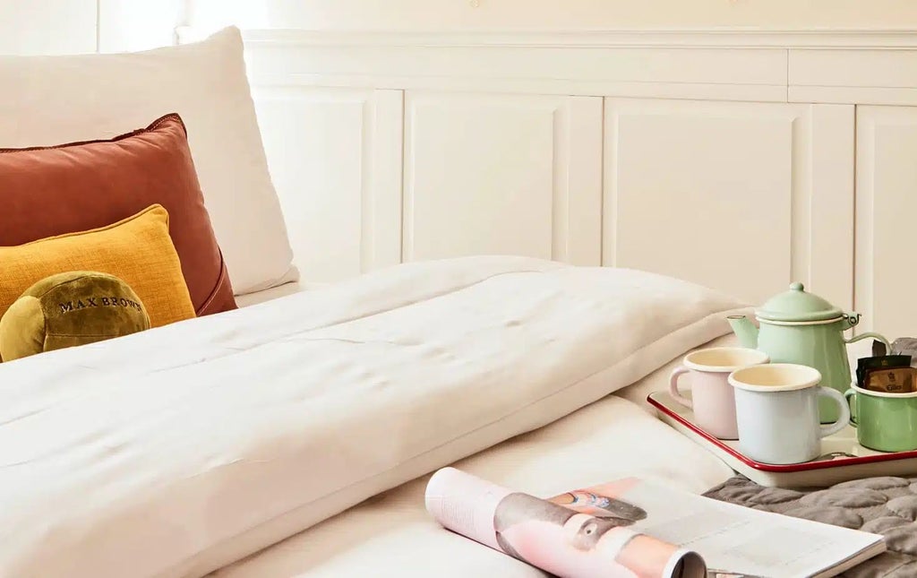 Minimalist small hotel room at scenset Brown Hotel Midtown, featuring sleek gray headboard, modern white linens, and warm ambient lighting in urban German setting