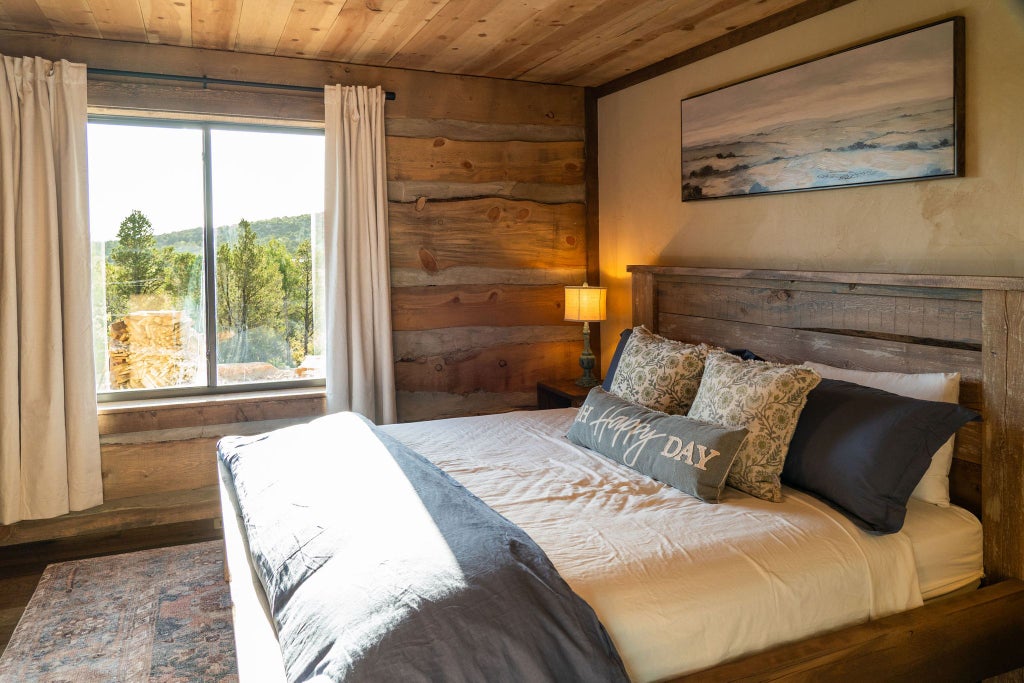 Rustic wooden lodge room with king bed, panoramic mountain views, earth-toned decor, and warm ambient lighting at scenset Mountain Ranch accommodation