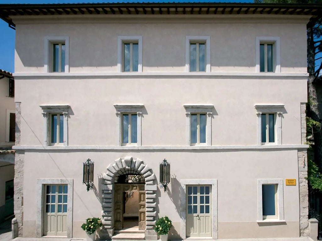 Elegant stone facade of historic Palazzo Seneca hotel in Norcia, Italy, with warm terracotta rooftops and traditional Umbrian architectural charm