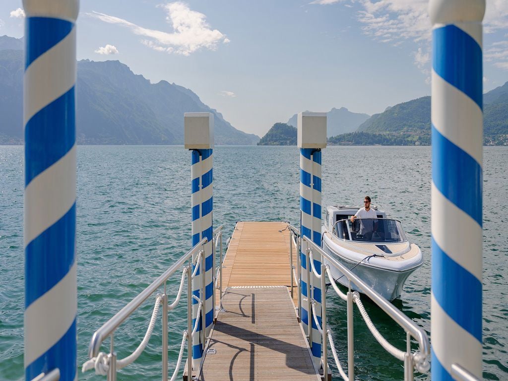 Elegant waterfront hotel with classic Italian architecture, featuring white facade, ornate balconies and palm trees along Lake Como