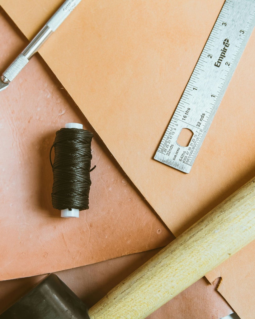 Italian artisan in his traditional workshop carefully crafting leather goods, surrounded by handmade accessories and tools