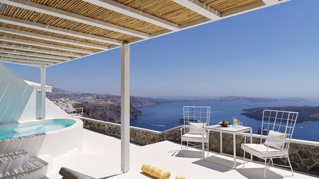 Luxurious white infinity pool overlooking stunning blue Aegean Sea with Santorini's iconic caldera and pristine architectural design at sunset