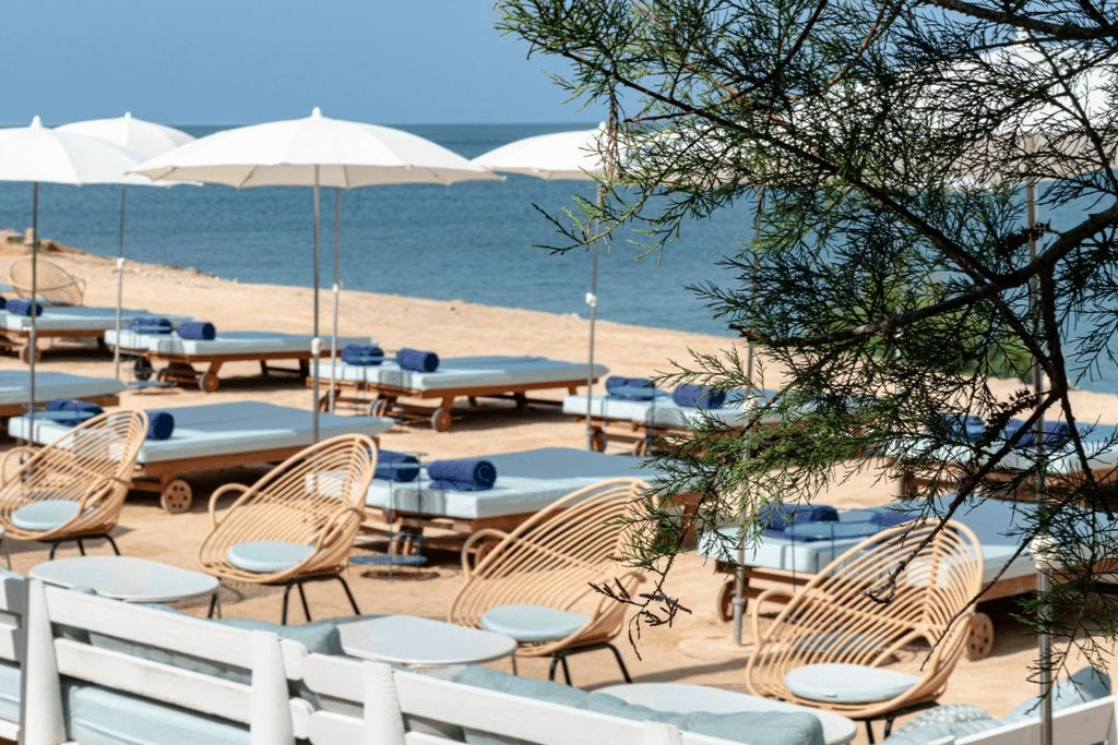 Whitewashed boutique hotel exterior with minimalist design, set against vibrant blue sky, showcasing Balearic Islands' luxurious Mediterranean architectural style
