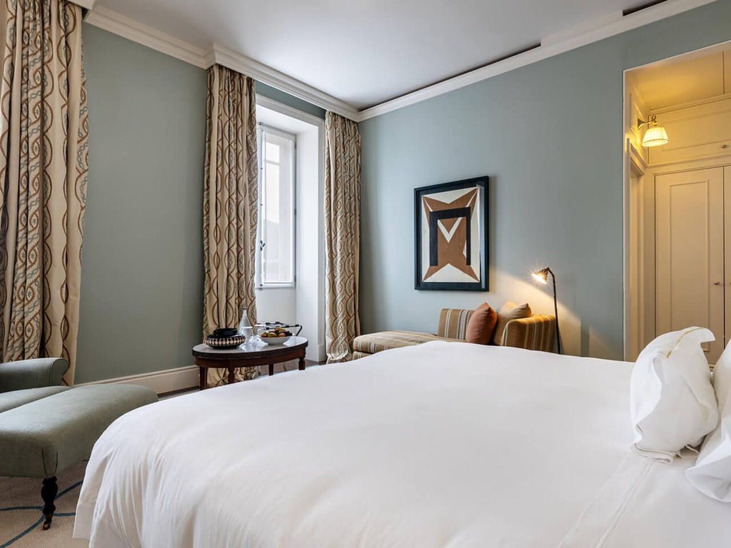 Elegant superior hotel room at Vidago Palace, featuring plush white bedding, ornate golden accents, and large windows overlooking lush Portuguese landscape