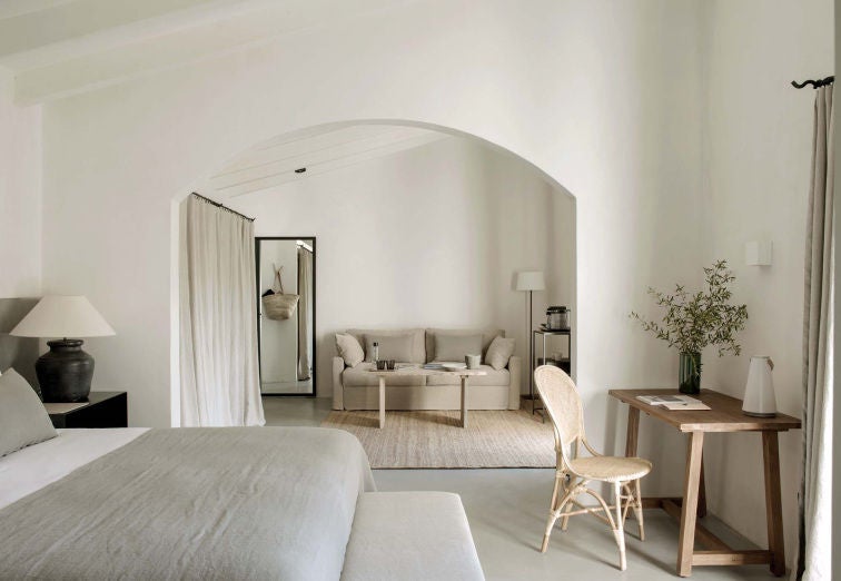 Elegant hotel suite with rustic stone walls, white linens, and wooden beams showcasing Mediterranean charm and modern luxury finishes