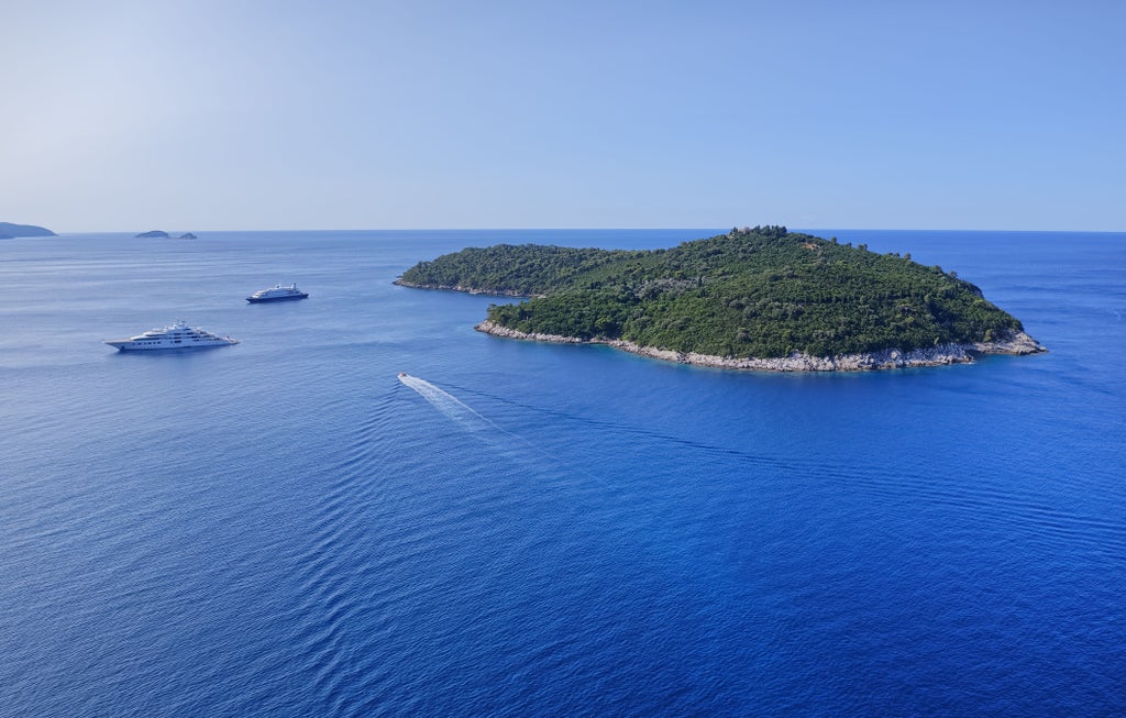 Luxury speedboat cruising crystal-clear Adriatic waters near Hvar, with emerald Pakleni Islands and dramatic coastline in background