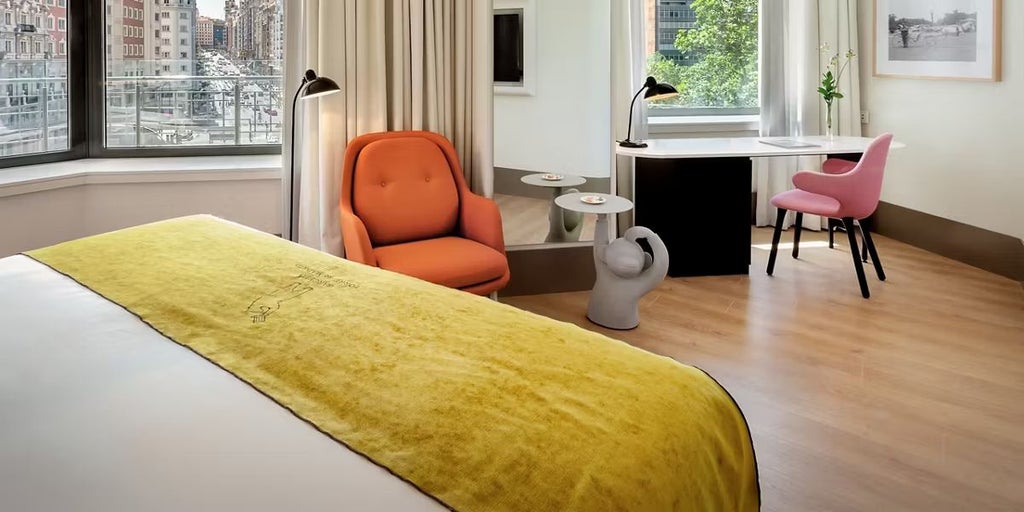 Luxurious hotel room with expansive city views, modern decor, floor-to-ceiling windows overlooking Madrid's vibrant skyline at sunset, elegant furnishings