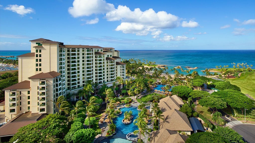 Luxurious beachfront resort with palm trees, azure waters, and modern Hawaiian-style architecture at tropical Ko Olina Beach Club in Hawaii