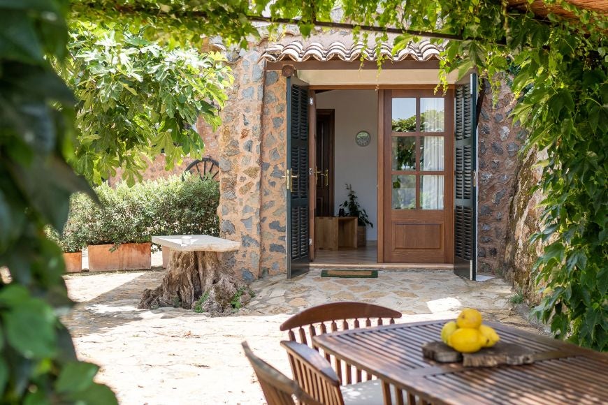 Serene garden cottage with stone walls, lush greenery, and elegant outdoor seating at luxurious Spanish retreat nestled in scenic landscape