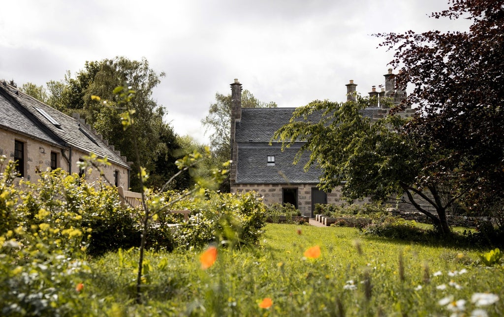 Elegant Scottish Highland hotel exterior with whitewashed stone walls, large windows, and manicured gardens under cloudy skies