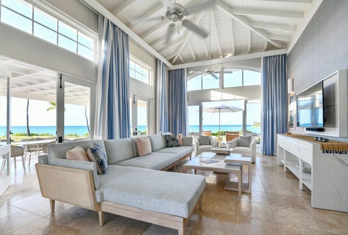 Luxurious pool suite with pristine white decor, sleek modern furniture, and expansive ocean views at an elegant Caribbean resort.