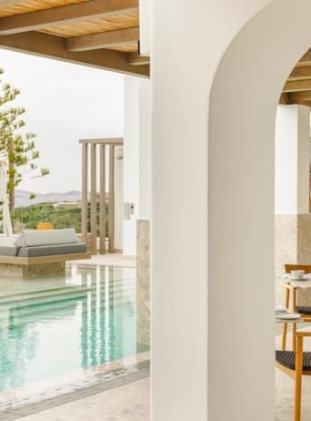 Luxurious white-washed Cycladic hotel with blue-domed architecture overlooking the azure Aegean Sea, capturing Mykonos' elegant coastal charm