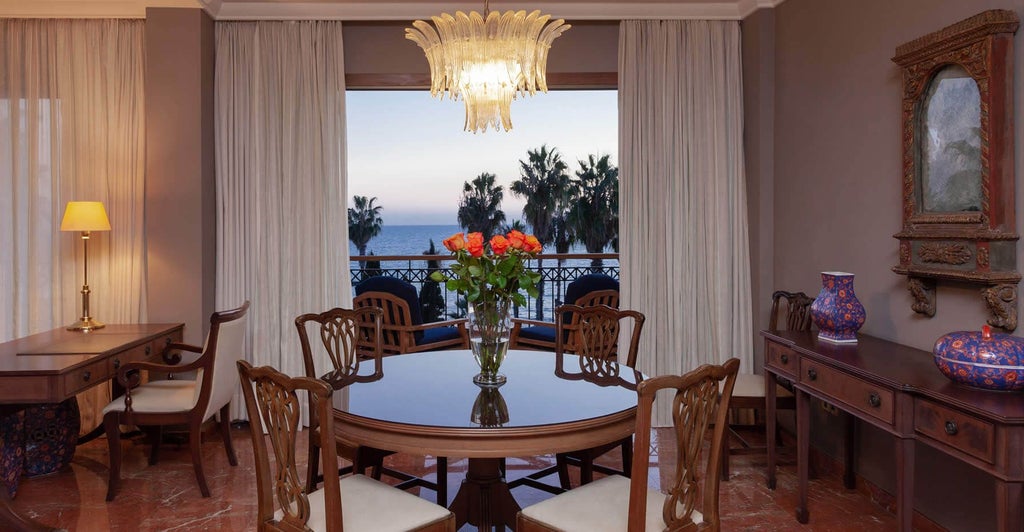 Spacious two-bedroom suite with modern furnishings, plush king beds, elegant marble bathroom, and panoramic sea view from private balcony at luxury Cyprus hotel