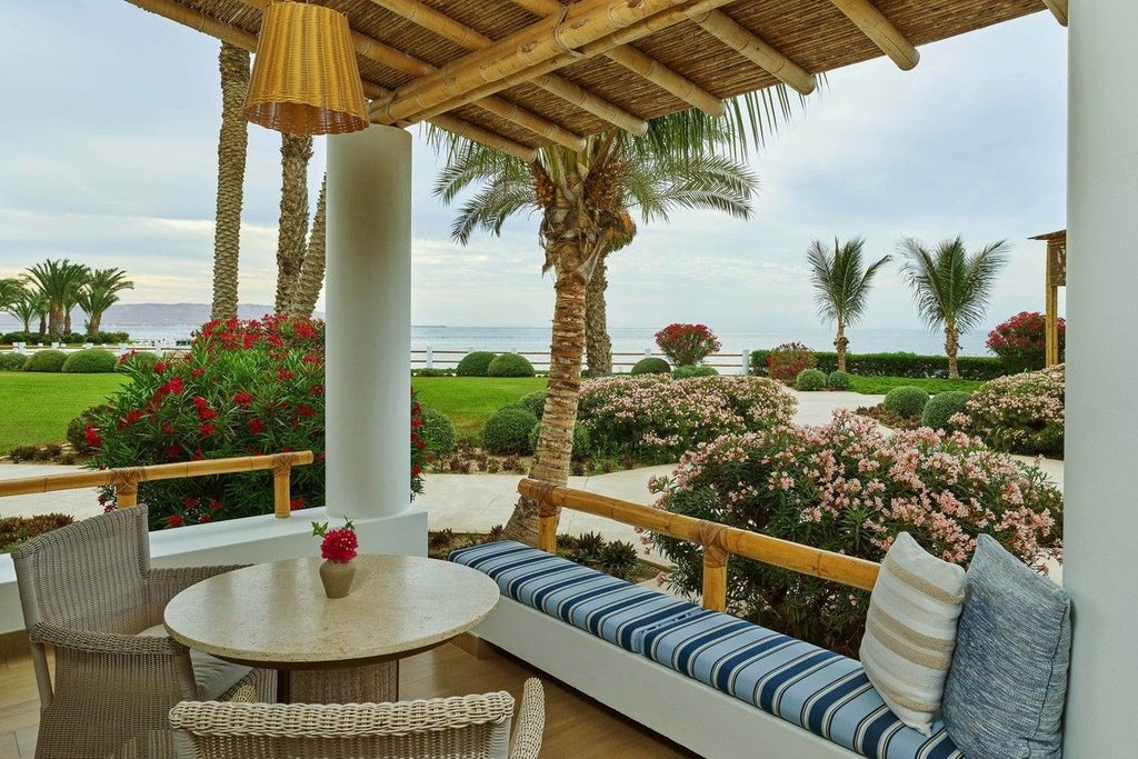 Luxury beachfront resort with modern white buildings nestled between palm trees and ocean, featuring infinity pools at sunset