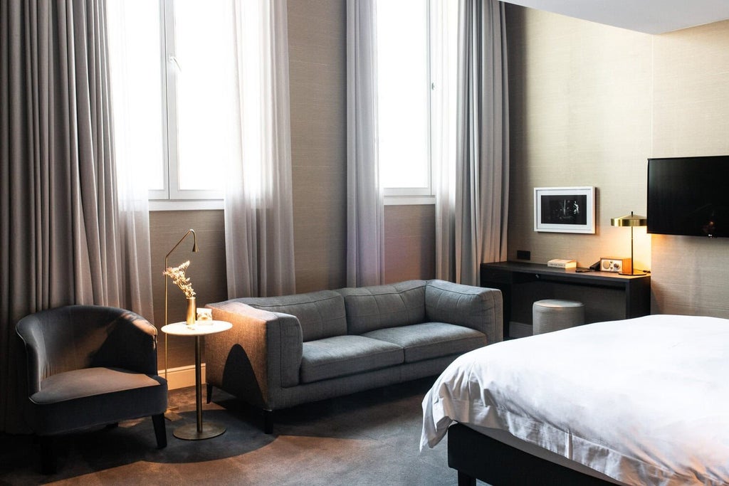 Spacious family room with plush white bedding, elegant wooden furnishings, large windows, and soft ambient lighting at luxurious Boutique Hotel in Belgian setting