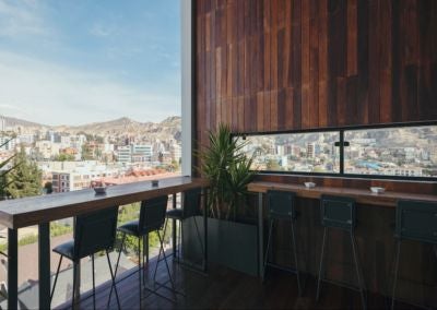 Modern glass-fronted Atix Hotel in La Paz, Bolivia, with sleek architectural design, urban backdrop of mountains, and contemporary luxury aesthetic