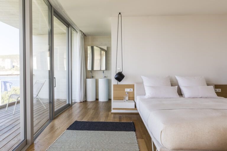 Luxurious Croatian hotel suite with modern design, panoramic sea view, minimalist white decor, and spacious balcony overlooking the Adriatic coastline