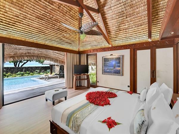 Luxurious overwater villa with private pool, wooden deck, and panoramic views of turquoise lagoon and lush mountains of Taha'a Island