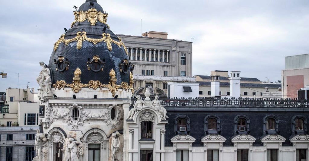 Opulent hotel suite in Madrid with modern decor, expansive windows overlooking Gran Vía, featuring elegant furnishings and sophisticated city view